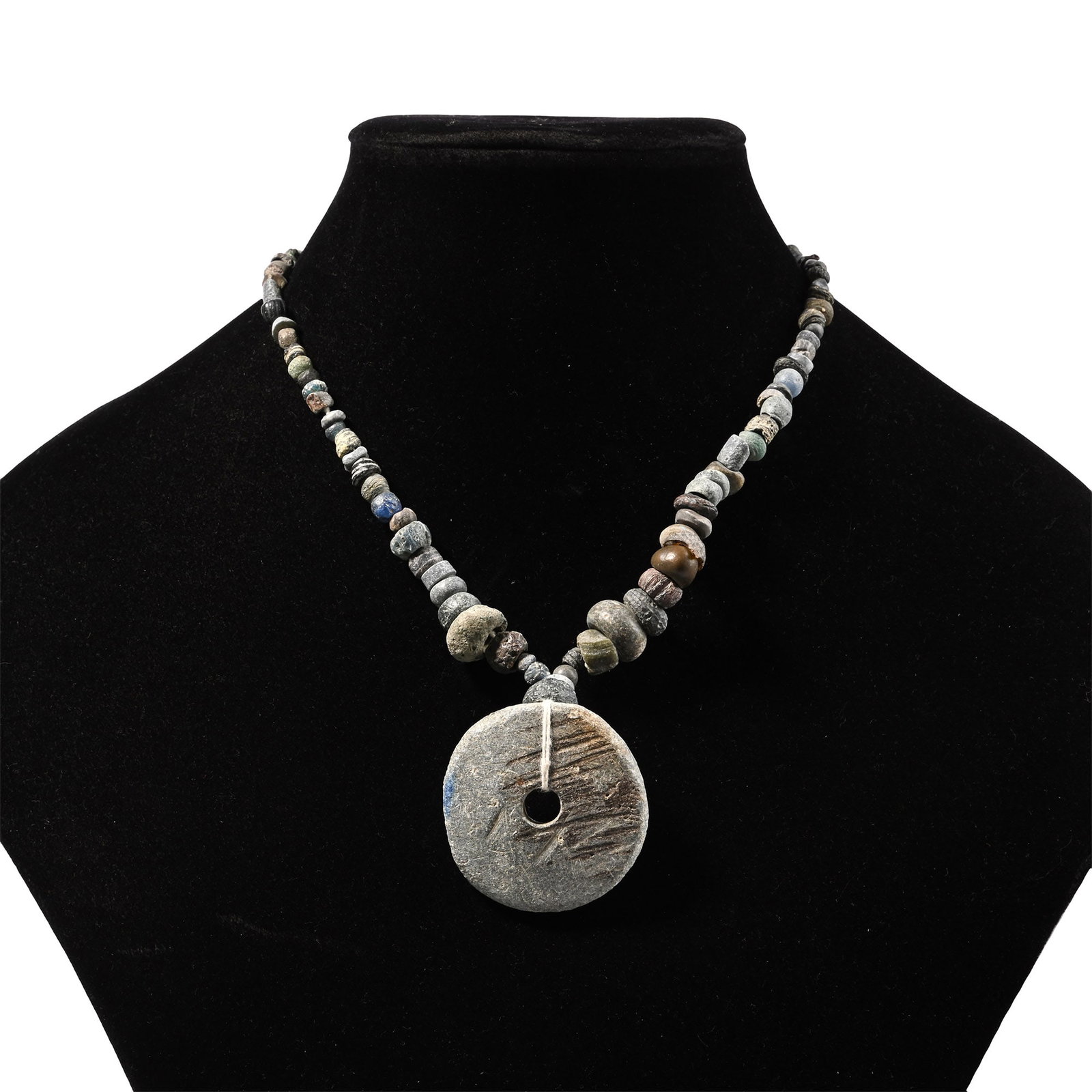 Western Asiatic Stone and Other Bead and Pendant Necklace String: 1st millennium B.C. and later. Composed of graduated mixed beads with a large discoid pendant, restrung. 57 grams, 34.5 cm (13 5/8 in.). [No Reserve] Ex Ancient Art Shop, Windsor, UK, 1990s. Ex privat