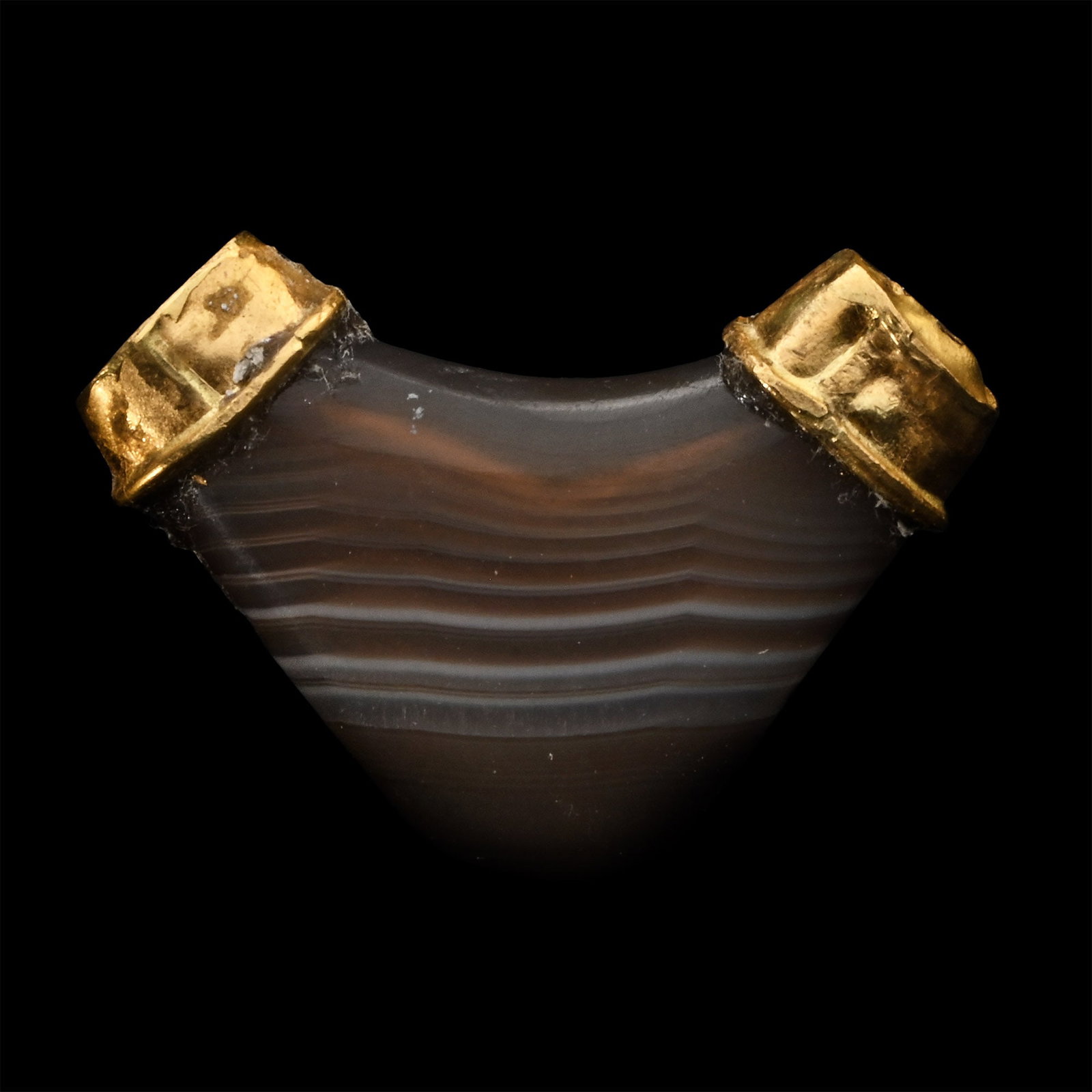 Achaemenid Banded Agate Elbow Bead: 6th-4th century B.C. Carved from agate with horizontal contrasting banding, with a later ellipsoid gold cap to each finial. 1.26 grams, 19 mm (3/4 in.). From the collection of a late Japanese gentlema