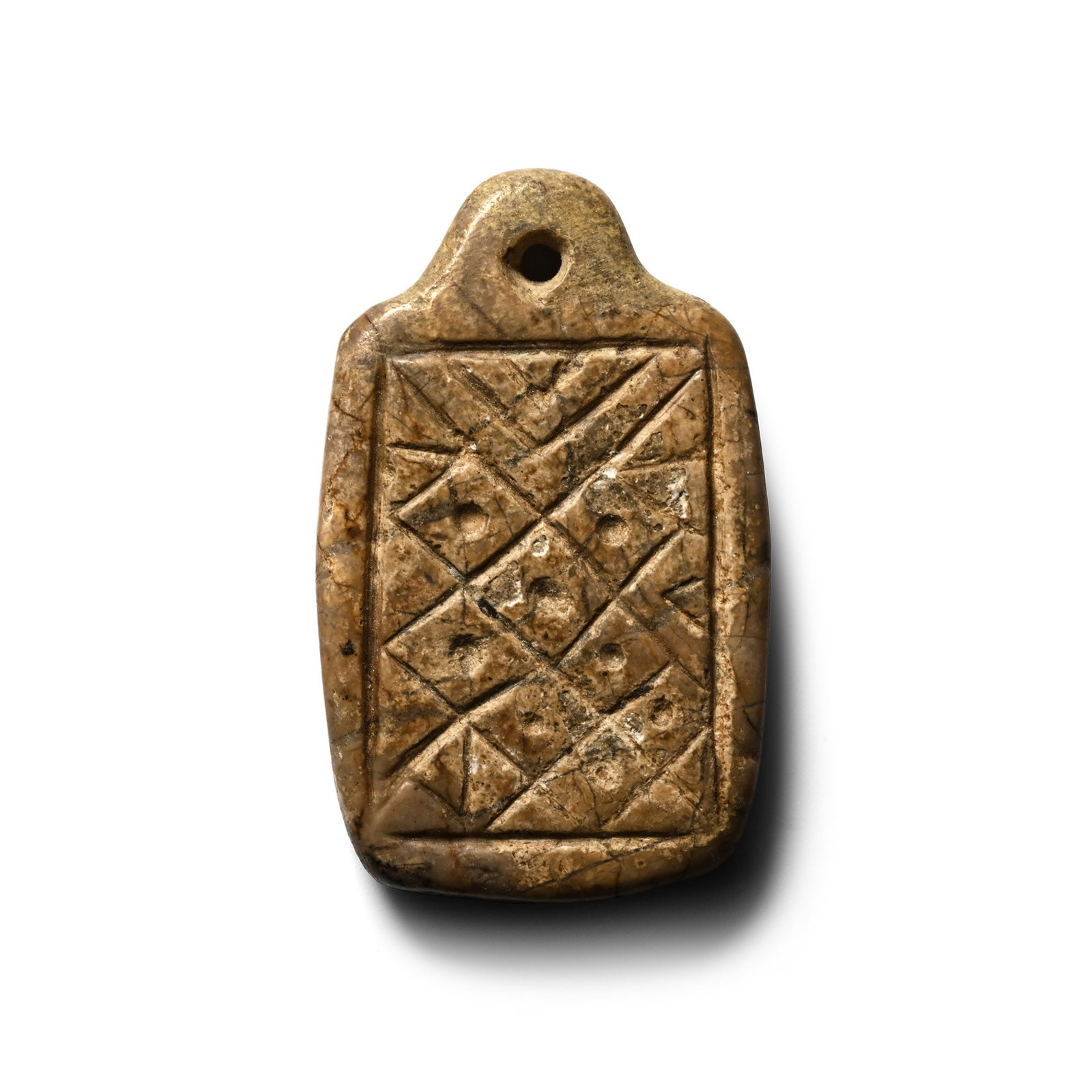 Western Asiatic Stone Geometric Pendant: Circa 14th-16th century A.D. Rectangular body with integral suspension loop and engraved grid of dot-in-lozenges on the obverse. Cf. for similar patterns (Pythagorean tetractys) in Islamic art Critchl
