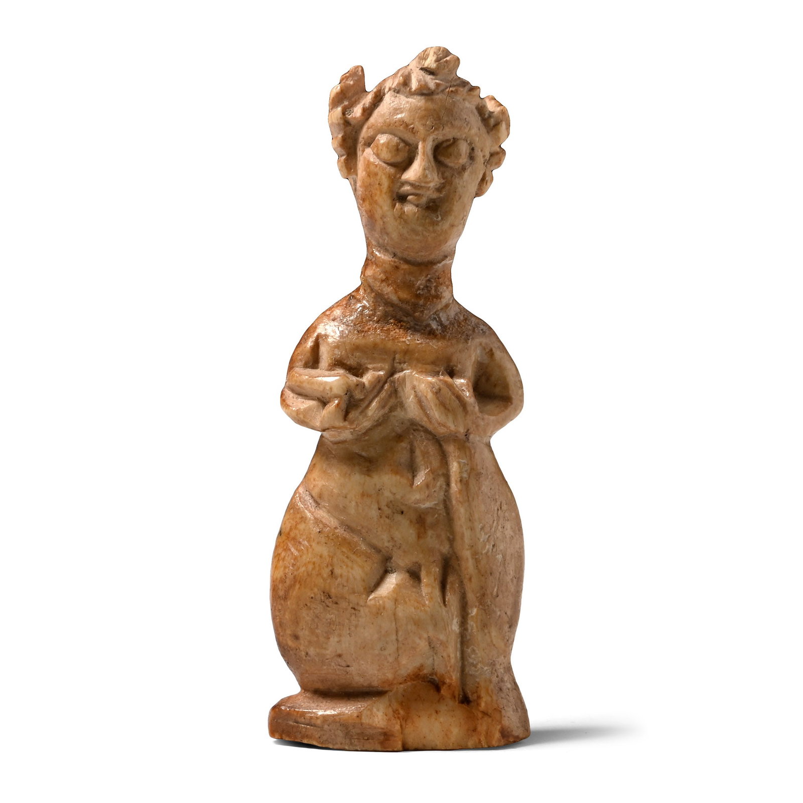 Sasanian Bone Fertility Figure: Circa 5th century A.D. Carved in the round as a standing female on a baseline; the hair drawn up into tight buns on either side of the head, high collar beneath the chin, hands cupping the breasts, vo