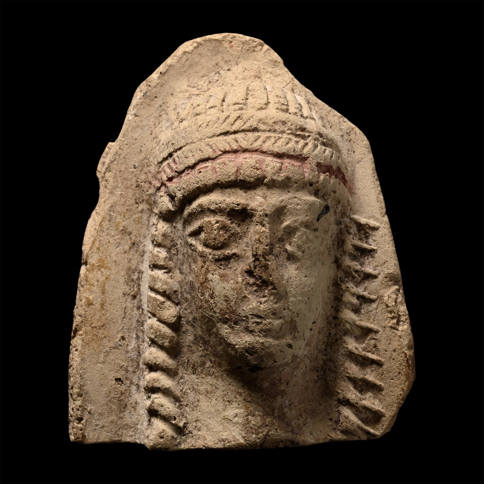 Western Asiatic Terracotta Idol Head: Circa 1st century B.C. Tongue-shaped panel with integrally-moulded facing female bust, hair in radiating braids, transverse headband, lateral plaits, exaggerated lentoid eyes; plain to reverse. 17.7 g