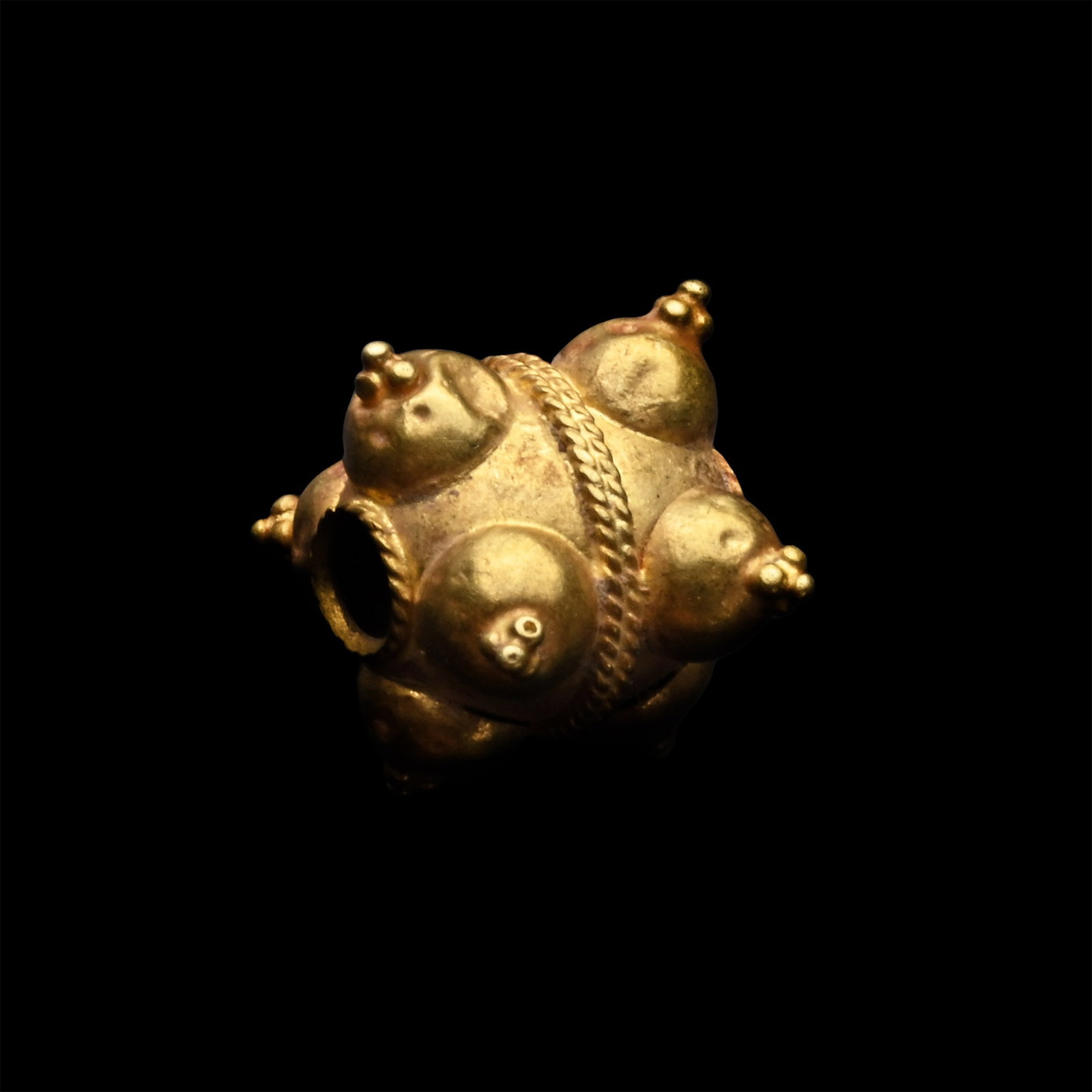 Western Asiatic Ornate Gold Bead: 1st millennium B.C. Composed of two hemispheres connected with a double filigree band, each hemisphere with four projecting bosses surmounted by granules. 0.44 grams, 8 mm (1/4 in.). Ex late Japanese 