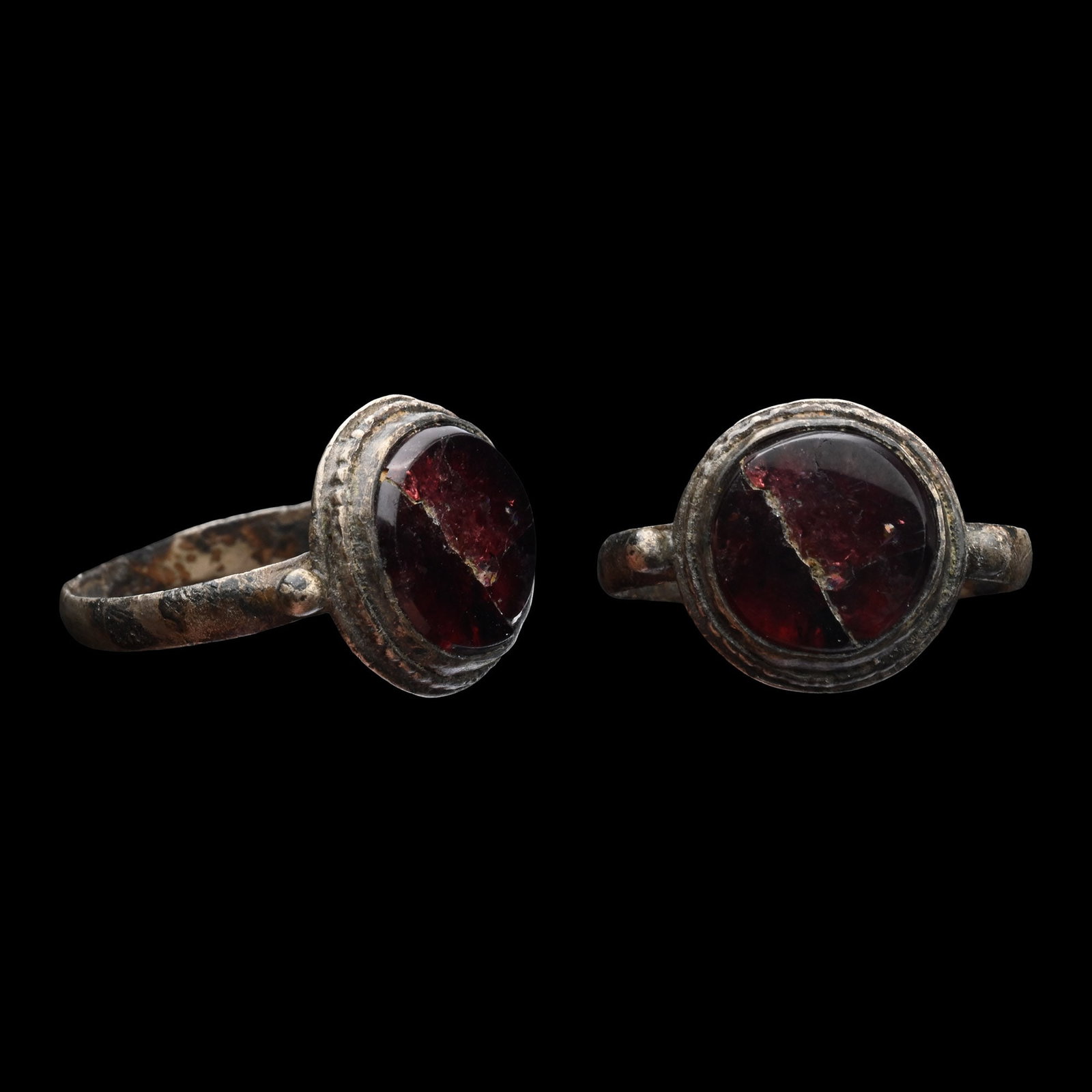 Dark Age Silver Ring with Garnet: Circa 6th-8th century A.D. Comprising a slender hoop with an applied granule on each shoulder flanking the circular bezel set with a table-cut garnet. 1.97 grams, 19.01 mm overall, 16.10 x 14.65 mm in