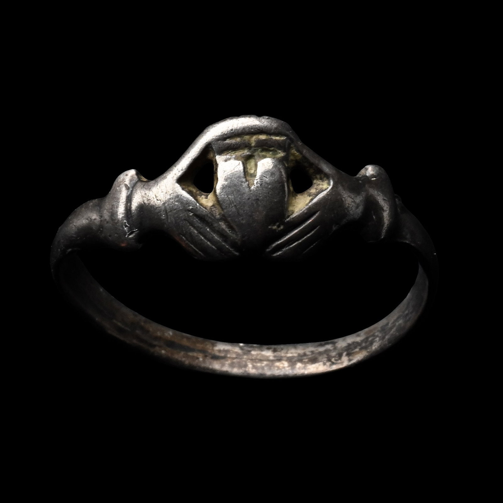 Post Medieval Silver Clasped Hands Holding Heart Ring: 17th century A.D. Claddagh ring with D-section hoop and the bezel formed as a heart held by two hands, topped by a crown. 1.96 grams, 22.10 mm overall, 19.19 mm internal diameter (approximate size Bri