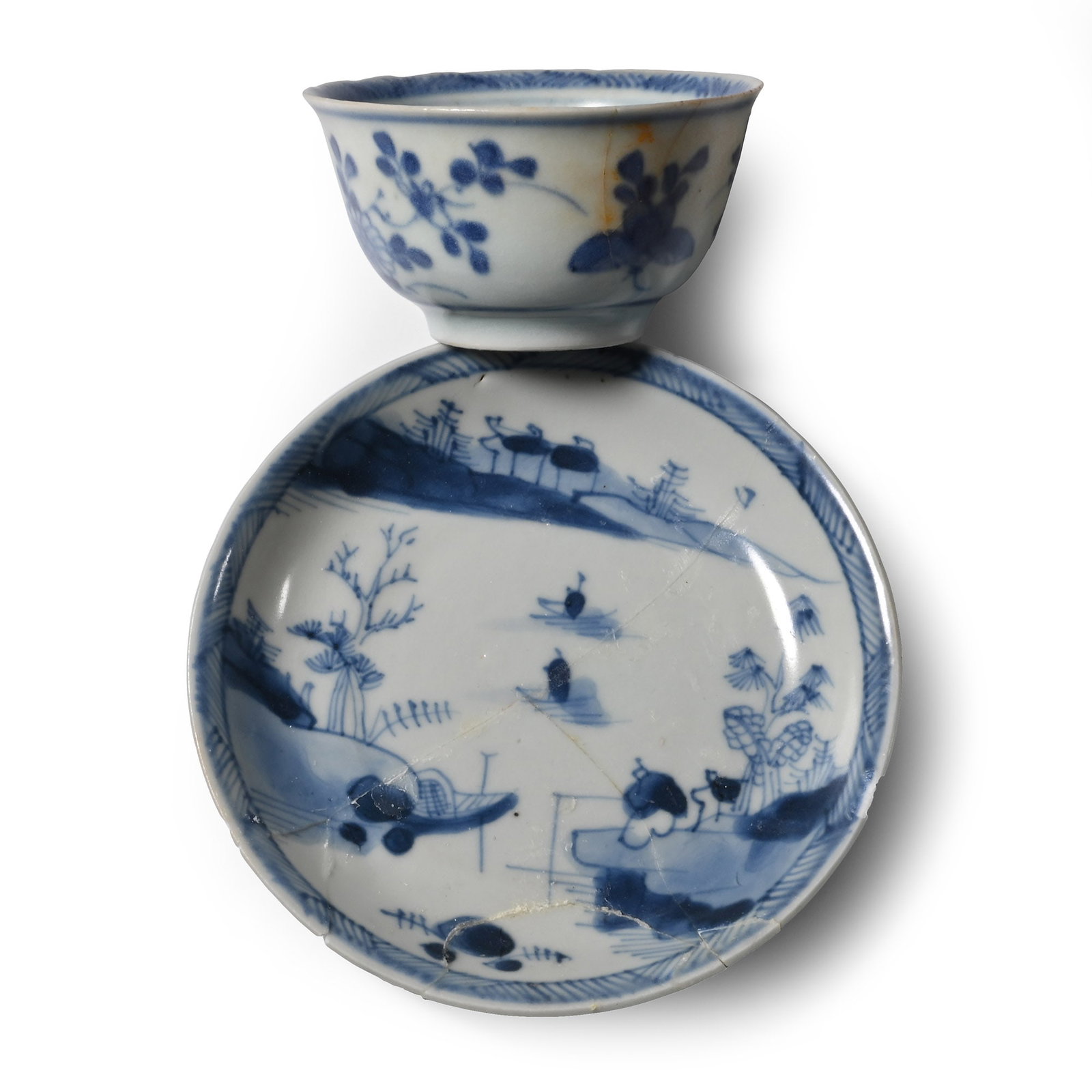 Ca Mau Cargo Shipwreck Glazed Blue and White Tea Bowl and Saucer: Early 18th century A.D. Comprising: a shallow plate with a lakeside scene, a fisherman on the foreground and floating boats in the distance; the bowl with painted flowers and butterflies to the outer 