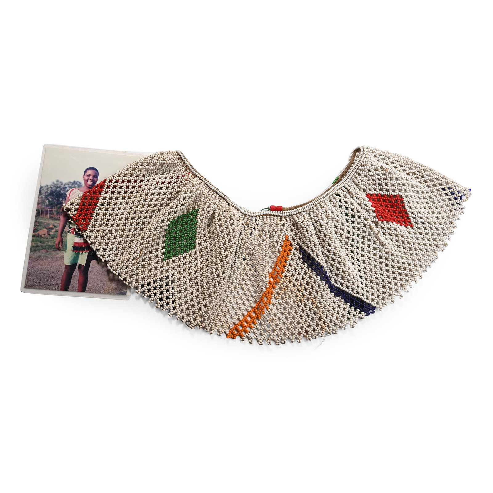 Zulu Woman's 'Umgexo' Beaded Collar and Photograph of an Unknown Zulu, a Descendant of the Owner,: 20th century A.D. A handmade wide collar composed mainly of white beads with colourful bands and lozenges; some beadwork has come undone. 485 grams total, necklline: 50 cm long (19 3/4 in.). [No Reser