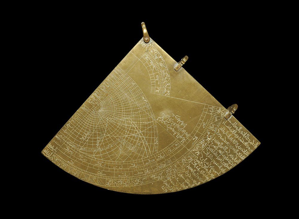 Islamic Brass Inscribed Navigational Quadrant: 20th century AD. A brass flat-section quadrant with suspension loop and two pierced lugs; one face with grid and numerical notation, the other with engraved arcs and notation. 1.2 kg, 16 cm (6 1/4").