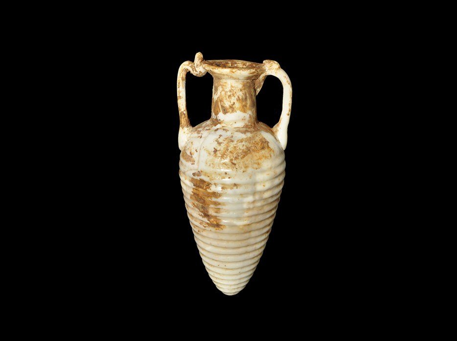 Roman Style White Glass Miniature Amphora: A miniature amphora with ribbed detail to the body, tubular neck, applied rim and applied trail handles. 33 grams, 11 cm (4 1/4"). Acquired on the London art market before 1995. [No Reserve]