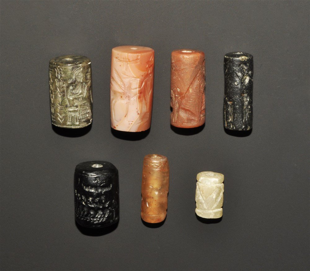 Near Eastern Style Stone Cylinder Seal Group: A mixed group of undated archaistic cylinders seals comprising:one black, two standing figures, altar, band of prisoners' one pink, standing figures and a griffin; one grey, opposed seated figures and