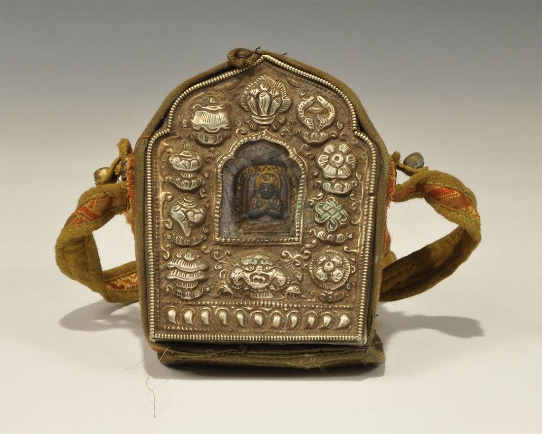 Chinese Style White Metal Reliquary Container in: An undated archaistic repoussé white metal box with glass window and cast figure behind on fabric backing, loops to the sides; contained in a fabric satchel with strap, quilted lid and button closure