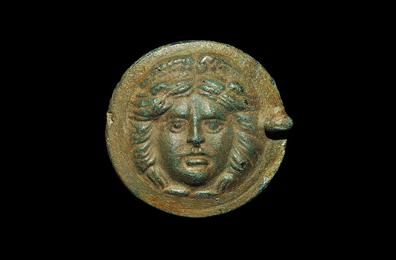 Roman Style Bronze Plaque with Loop: An undated archaistic cast convex discoid plaque or lid with pierced lug to one edge, the central motif a Gorgoneion modelled in high relief. 33 grams, 52 mm (2"). Ex Morris collection, Buckinghamshir