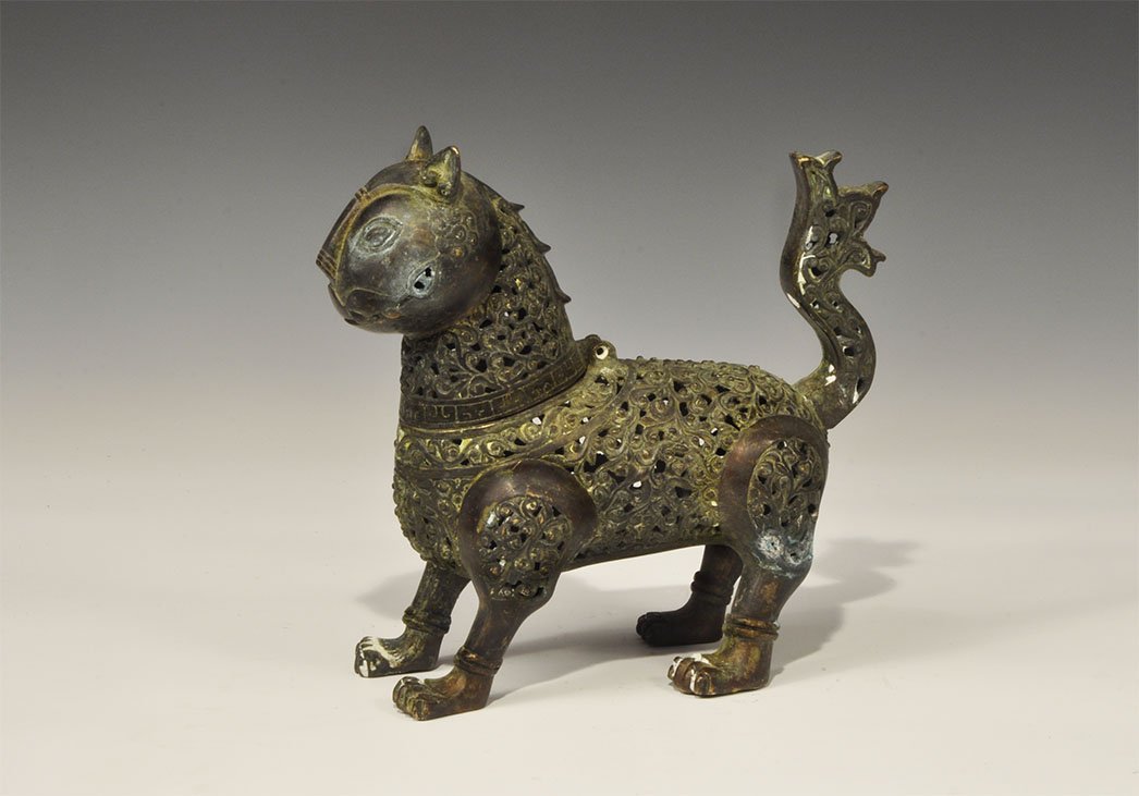 Islamic Style Pierced Bronze Animal Incense Burner: An undated archaistic openwork incense burner in the form of a standing lion with erect ears and recurved tail, the head a separate casting hinged at the neck; openwork neck, flanks, shoulders and hip