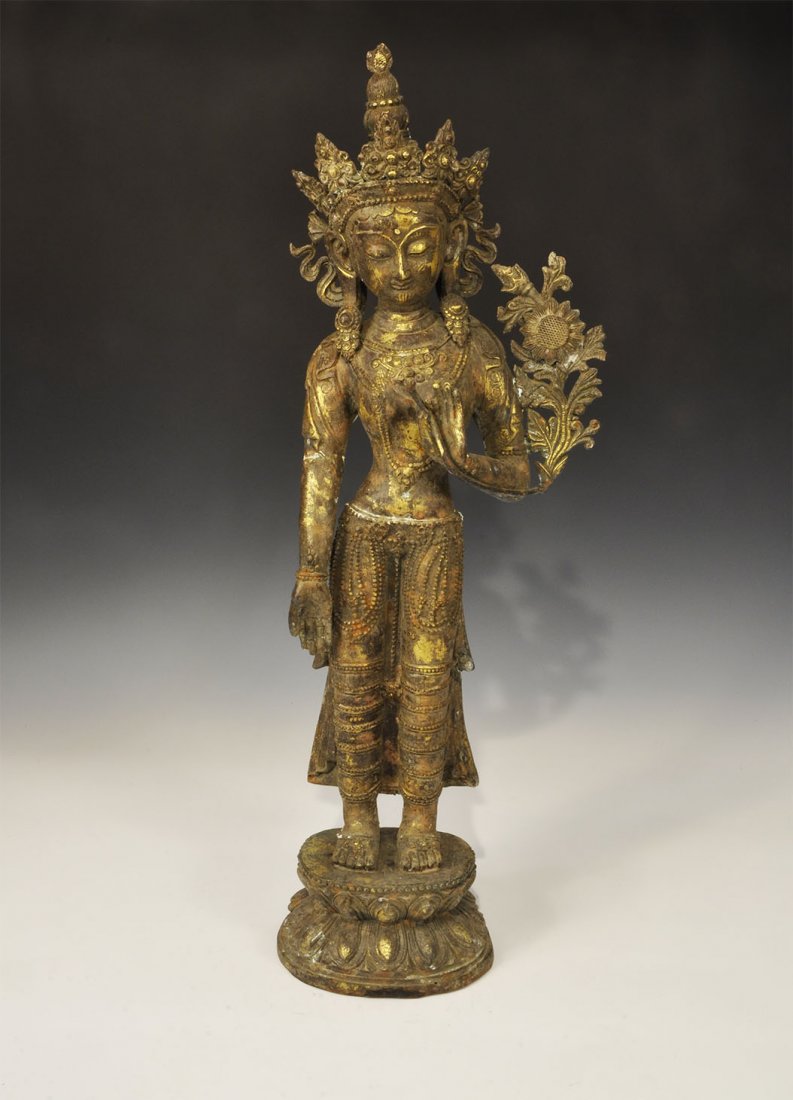 Chinese Thai Style Large Gilt-Bronze Tara Statuette: An undated archaistic cast gilt-bronze statuette of Tara standing with the right hand extended in the mudra gesture of wish fulfilment and the left raised holding the stem of a flower. 7.2 kg, 72 cm (