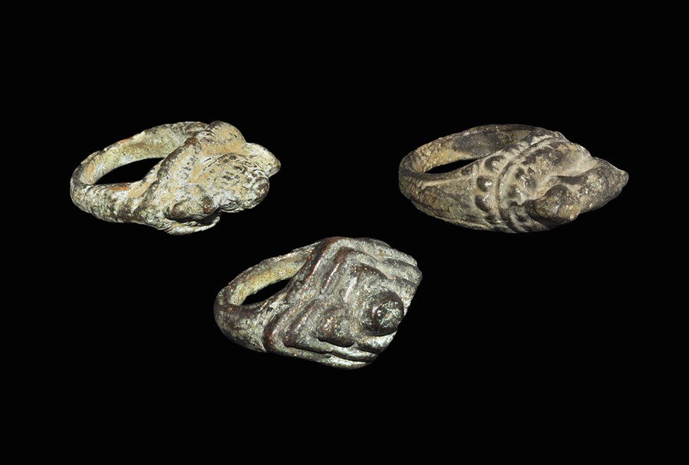 Cambodian Bronze Ring Group: 19th-20th century AD. A mixed group of three finger rings, each with D-section hoop, one with stepped bezel one with an elephant and one with a domed building. 111 grams total, 37-40 mm (1 1/2"). Prop