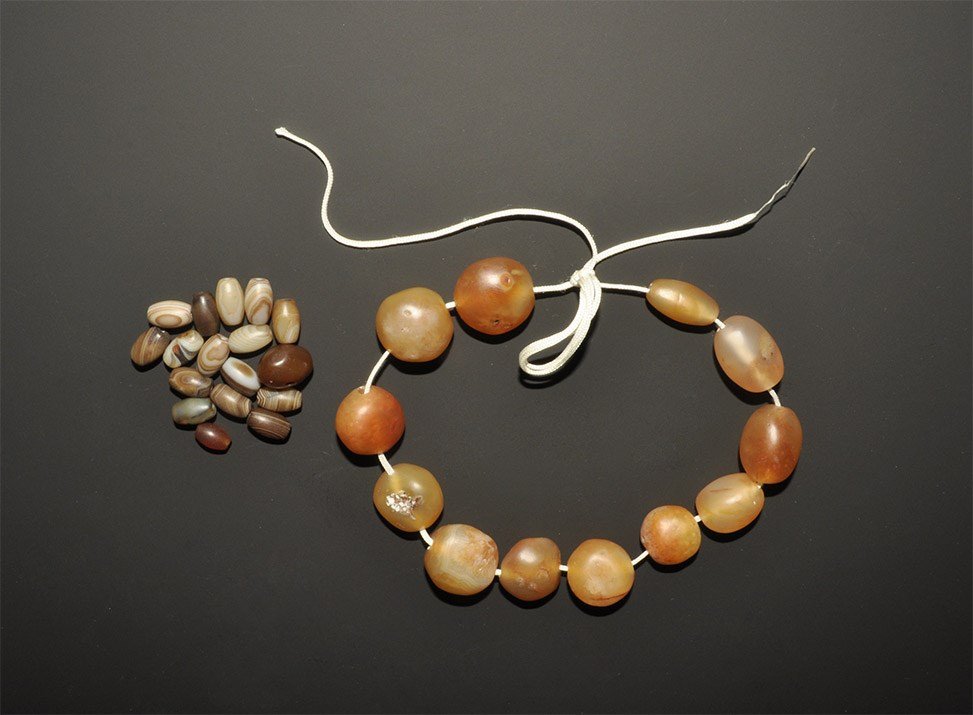 Near Eastern Style Agate Bead String and Others: A mixed group of undated archaistic globular agate beads on a modern string, and a group of mainly fusiform agate beads. 76 grams total, string; 21.5 cm (8 1/2"). Acquired UK art market, 1980s. [29, N
