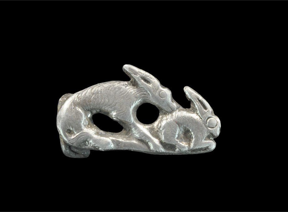 Roman Style Silver Hare and Hound Brooch: An undated archaistic cast plate brooch in 2nd century AD style, featuring a hare and hound on a baseline, fur texture to both; spring, pin and catchplate to the reverse. 7.98 grams, 29 mm (1 1/4"). P