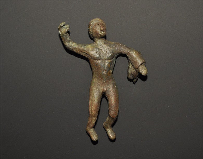 Roman Style Bronze Hercules Figure: An undated archaistic cast figurine of Hercules with cloak over the left forearm, right hand raised. 198 grams, 10.5 cm (4"). Property of a Cambridgeshire gentleman. [No Reserve]