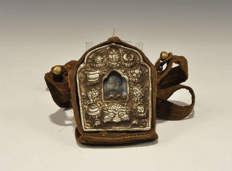 Chinese Style White Metal Reliquary Container in: An undated archaistic repoussé white metal box with glass window and cast figure behind on fabric backing, loops to the sides; contained in a fabric satchel with strap, quilted lid and button closure