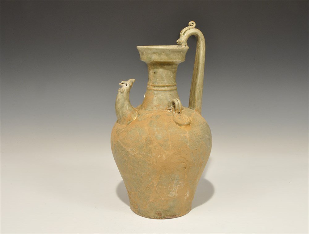 Chinese Cambodian Style Ceramic Cockerel Jug: An undated archaistic celadon ware jug with waisted neck, broad flange rim, animal-head spout, zoomorphic handle, two loops to the shoulder with rosette pads. 16 kg, 31 cm (12 1/4"). Acquired on the L