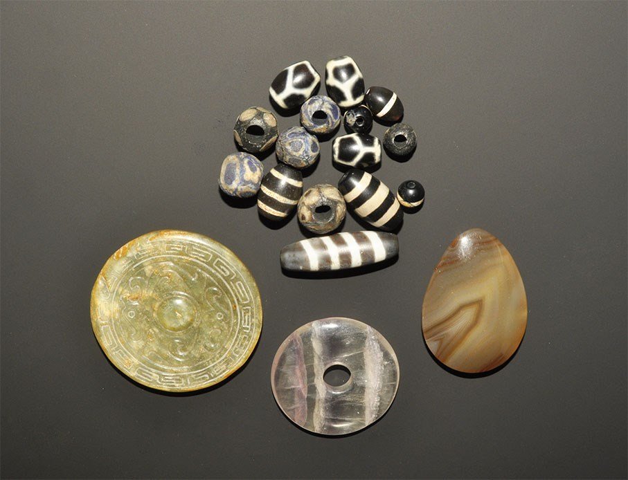 Chinese Style Mixed Bead and Artefact Group: A mixed group of undated archaistic items comprising: a piriform polished stone panel with scoop to one face; a crustal ring; a stone disc with central boss, two serpents and band of geometric ornamen