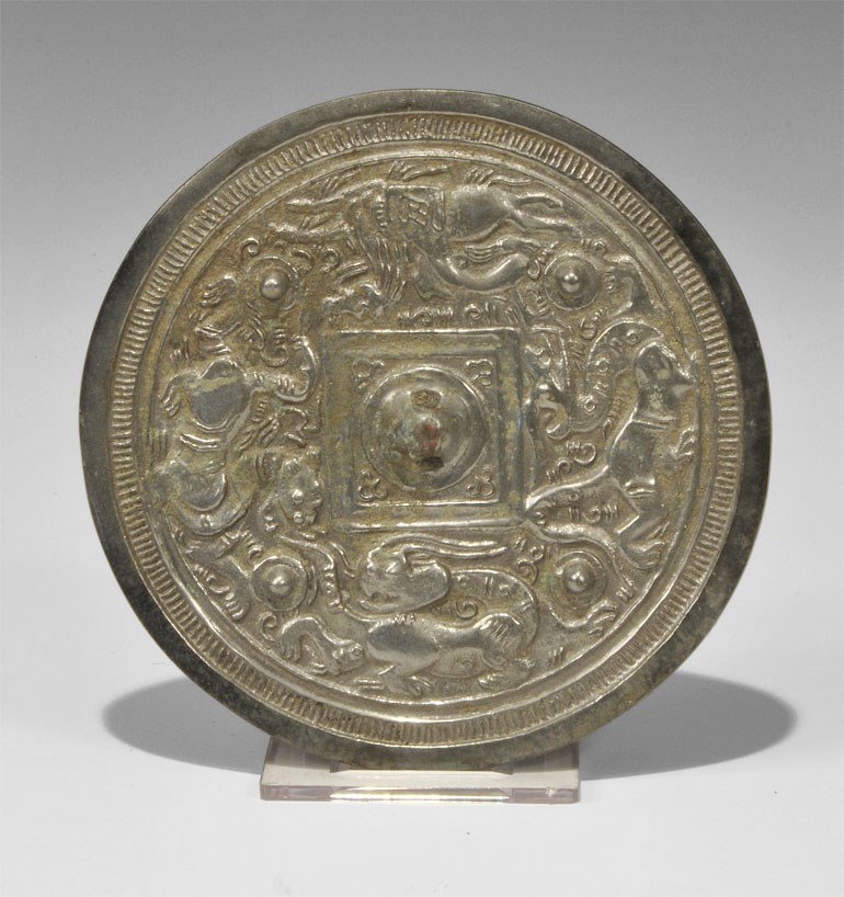 Chinese Style Bronze Figural Mirror: Han Dynasty, 206 BC-220 AD. A small cast-bronze disc mirror with one tinned and polished surface; to the reverse, a central pierced lug within a frieze of running mythical beasts. 238 grams, 12 cm (4 