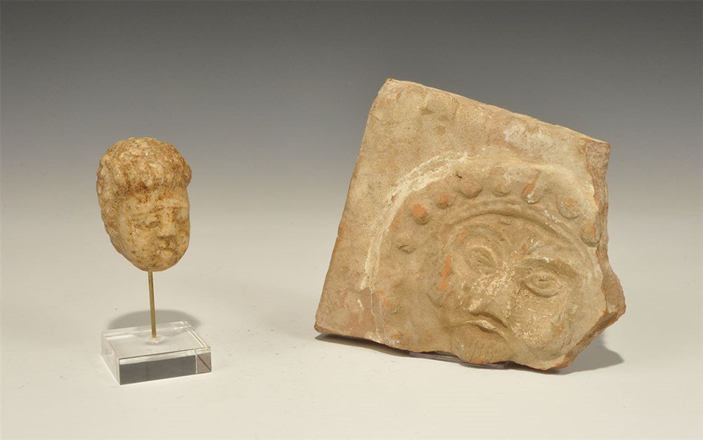 Byzantine and Later Artefact Group: 5th-12th century AD. A mixed group of items comprising: a carved stone head of a boy with fleshy features, ribbed hair, mounted on a custom-made stand; a terracotta tile fragment with lion-mask within