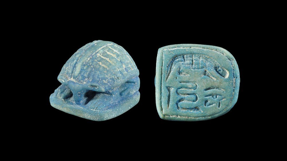 Egyptian Glazed Composition Hieroglyphic Scarab: Ptolemaic Period, 332-30 BC. A blue scarab on a D-shaped base with intaglio hieroglyphic text and crocodile. 7.48 grams, 23 mm (1"). From an old Swiss collection; acquired in Beirut before 1980. [No R