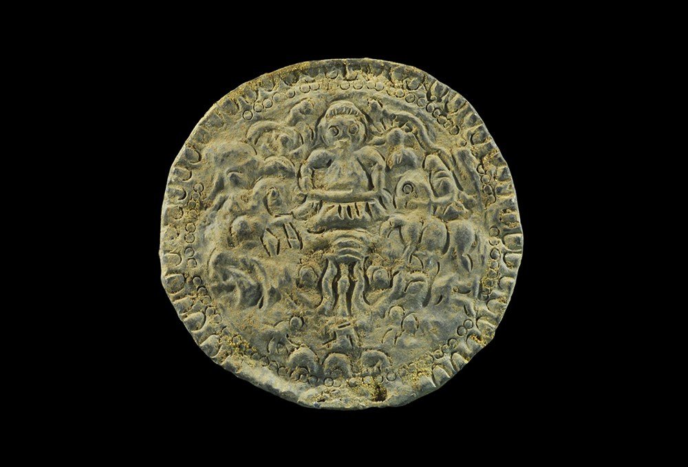 Greek Thracian Lead Votive Plaque: 5th-3rd century BC. A cast discoid plaque with billetted border and pelletted ring, central scene of a facing worshipper and tripod altar, sun with radiating beams to the right, vegetation and punched