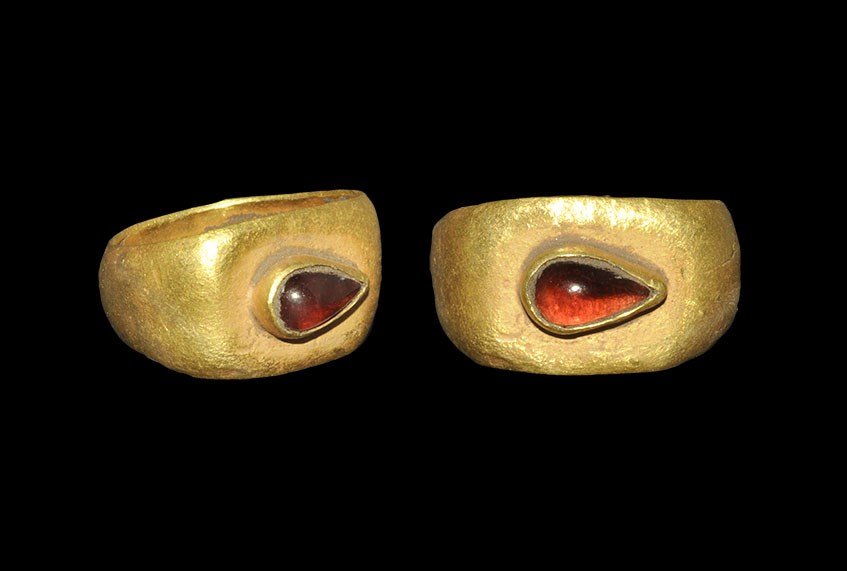 Roman Gold Garnet Cabochon Ring: 2nd-3rd century AD. A C-section hoop with expanding shoulders, flat bezel with piriform collar containing a cabochon garnet. 3.87 grams, 21 mm overall, 16.95 mm internal diameter (approximate size Bri