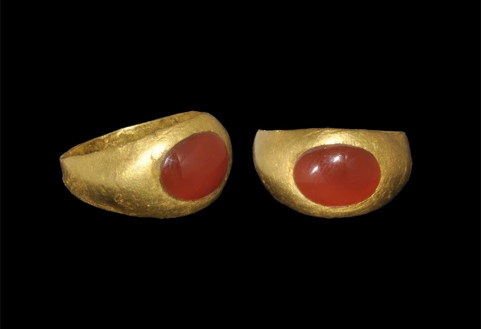 Roman Gold and Sard Ring: 1st-2nd century AD. A finger ring with hollow hoop, expanding shoulders and inset sard cabochon. 5.42 grams, 19 mm overall, 14.68 mm internal diameter (approximate size British G 1/2, USA 3 3/4, Europ