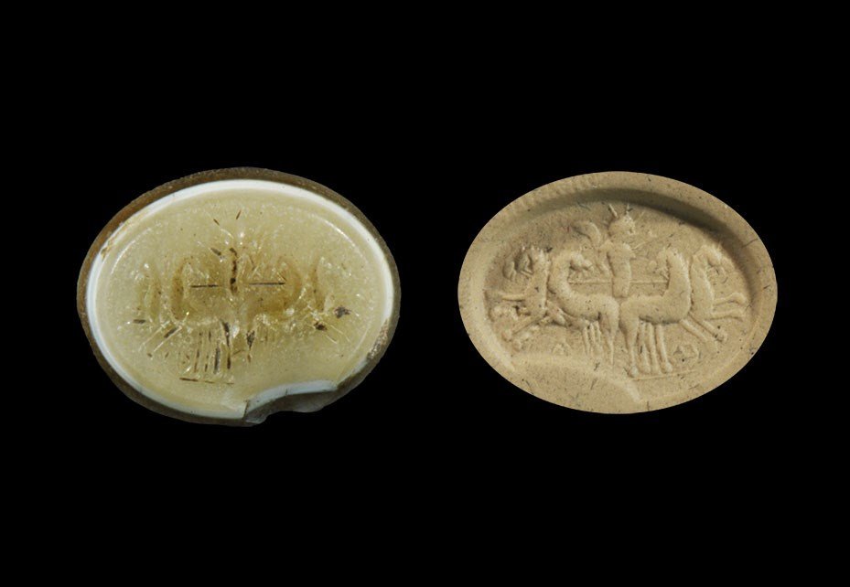 Roman Stone Intaglio of Sol in Facing Quadriga: 2nd-3rd century AD. A carved banded stone elliptical plaque with intaglio design of Sol with radiant crown above four horses. 1.60 grams, 17 mm (3/4"). UK art market, acquired prior to 1980.