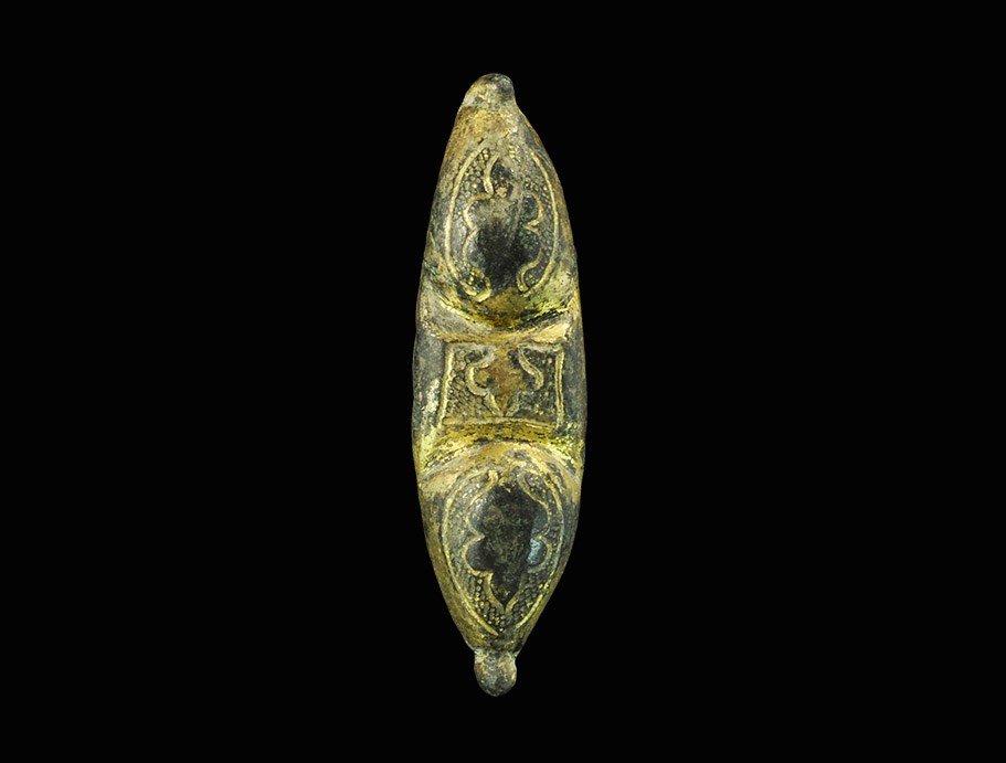 Byzantine Gilt-Bronze Equal-Arm Brooch: 6th-9th century AD. A cast equal-arm brooch, scaphoid in plan, with two ovoid panels and a central rectangle; in each panel a reserved leaf on a hatched field; pin-hinge and catchplate to the reverse.