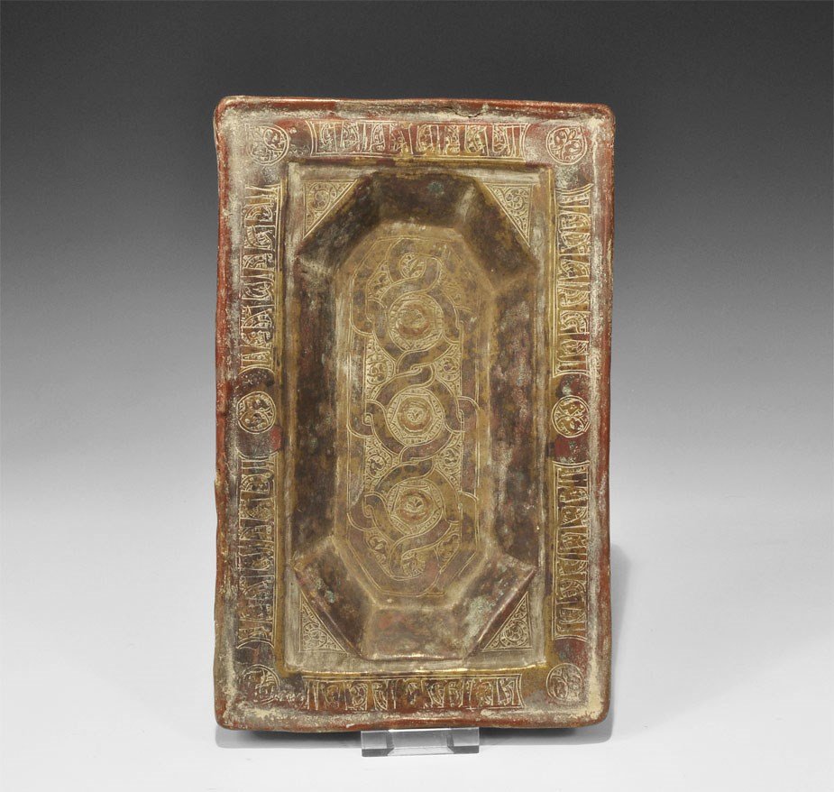 Islamic Gilt-Copper Calligraphic Dish: 17th-18th century AD. A rectangular sheet dish with octagonal central recess; the outer border decorated with a band of calligraphic text and roundels, the recess with a complex guilloche reserved aga