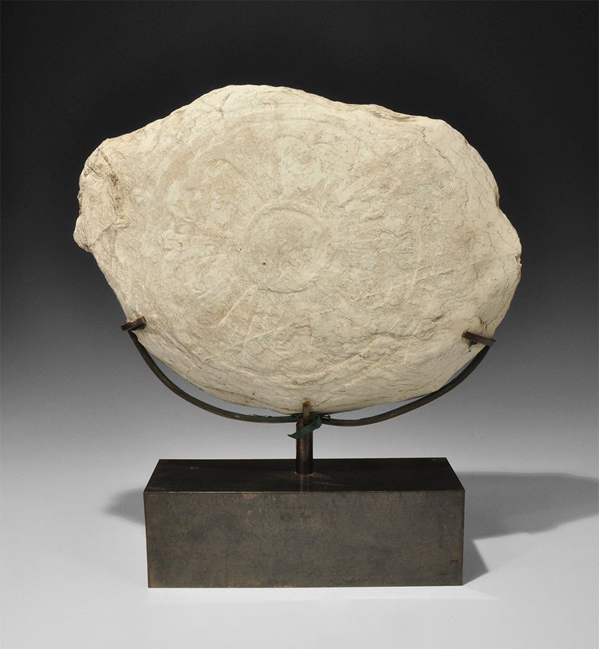 Islamic Persian Limestone Plaque with Geometric Design: An undated oval limestone plaque with a radiating circular geometric design, a circular medallion bearing an inscription in Arabic script. 11.7 kg, 40 cm (15 3/4"). Silk collection, London, UK; formed