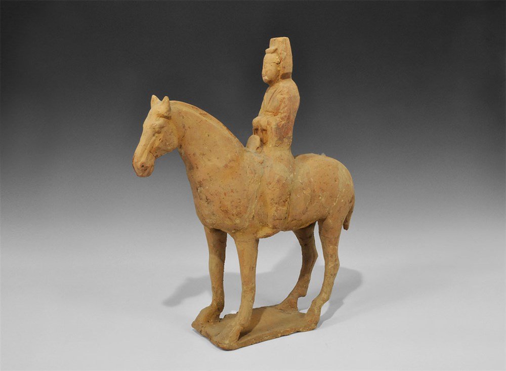 Chinese Ceramic Redware Horse and Rider: Tang Dynasty, 618-906 AD. A terracotta horse and rider figurine on a rectangular base; red and black pigment to the rider's clothing, white and red to the horse's body; hollow to the underside. 2 kg,