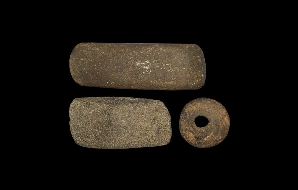 Stone Age Perforated Axe and Spindle Whorl Group: Neolithic to Bronze Age, 7000-1600 BC. A group of three items comprising: a ground Neolithic basalt axe with single cutting edge and rounded butt, with tapered perforation for hafting (with inked refe