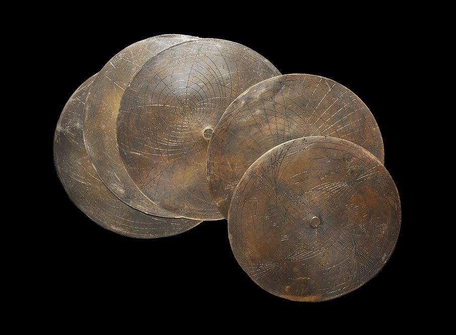 Islamic Style Astrolabe Navigational Disc Group: A group of five undated archaistic sheet bronze astrolabe discs, each with engraved navigational data, numerical notation and geometric figures. 413 grams, total, 15 cm (6"). Property of a Buckinghams