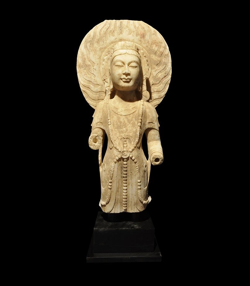 Gandharan Style Marble Buddha Statue: An undated archaistic carved statue of the Buddha with nimbus of flame behind the crowned head; mounted on a custom-made stand 24 kg, 74 cm including stand (29"). Private collection, S.E. London; acqu