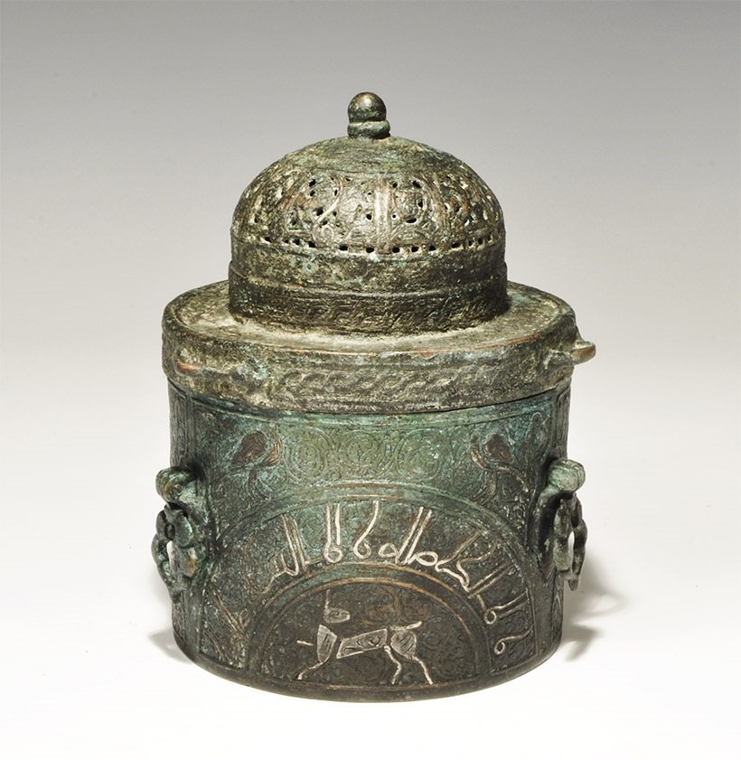 Islamic Style Bronze Calligraphic Lidded Caddy with: An undated archaistic cast cylindrical ewer with three drop handles to the body, domed lid with openwork centre, three strap handles; three arched bands of silver-inlaid calligraphic text to the body 