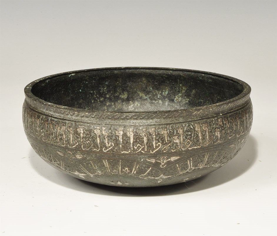 Islamic Style Bronze Caligraphic Bowl with Silver Inlay: An undated archaistic cast bowl with panels of silver-inlaid animal and plant ornament to the underside, band of silver-inlaid calligraphic text below the rim. 1.2 kg, 19.5 cm (7 3/4"). Ex South East 