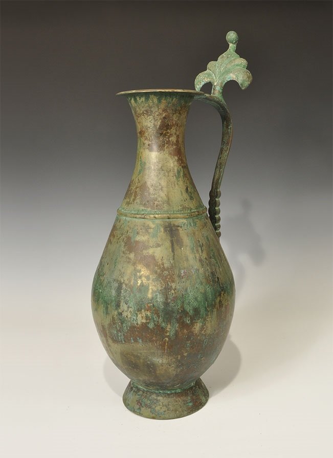 Islamic Style Bronze Ewer: An undated archaistic piriform ewer with flared base, piriform body, waisted neck with flange rim; the D-section handle curved with beast-head detail below, palmette panel and thumb-pad to the upper f