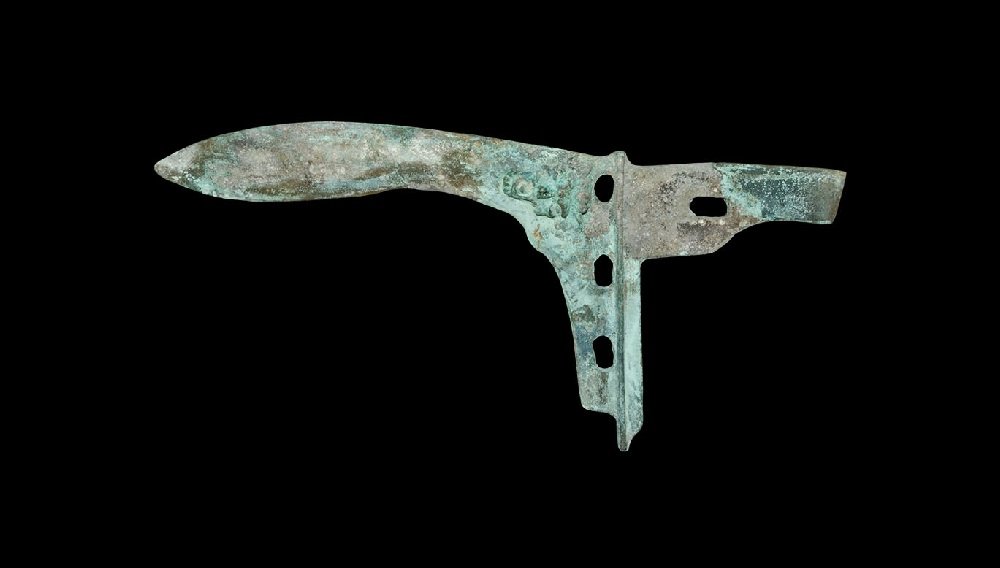Chinese Han Style Bronze Halberd Blade: An undated archaistic cast halberd head with leaf-shaped blade, transverse rib with attachment holes, rectangular extension to the rear; lion-head in high-relief to one face of the blade. 242 grams, 2