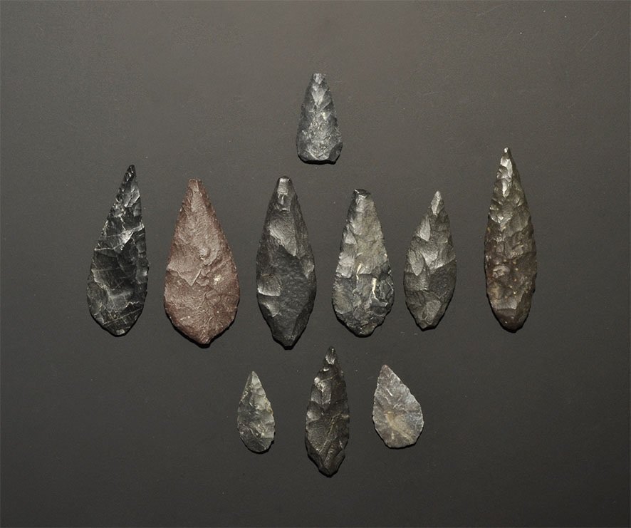 Stone Age Saharan Arrowhead Group: Neolithic, 6000-3000 BC. Group comprising: three small bifacial 'bird-hunting' points of leaf form and seven similar but larger points of leaf form; all finely made in a dark grey-black chert and show