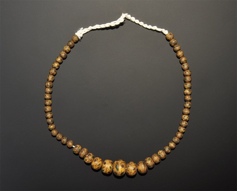 Near Eastern Gabari Style Glass Bead String: A graduated string of undated archaistic globular beads in yellow with red and blue trails. 60 grams, 40 cm (15 3/4"). Acquired on the London art market before 2000. [No Reserve]