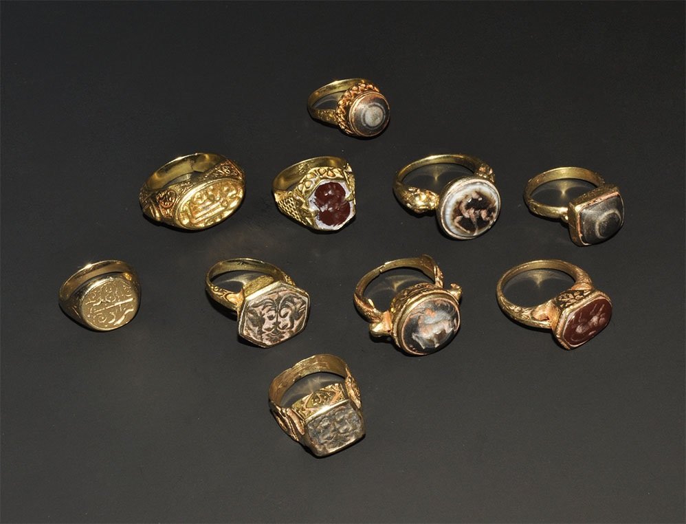 Islamic Style Gilt Finger Ring Group: A mixed group of undated archaistic finger rings comprising: two with 'banded agate' cabochon; four with integral intaglio; four with hardstone intaglio insert. 78 grams total, 21-34 mm (3/4 - 1 1/4")