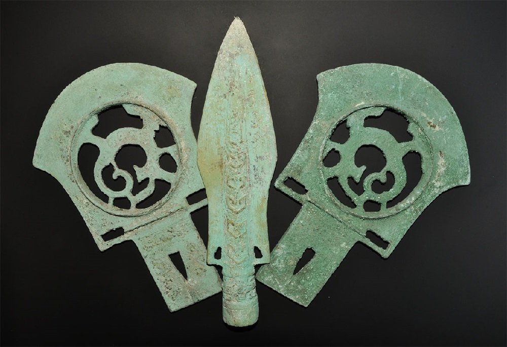 Chinese Style Spearhead and Poleaxe Group: A mixed group of undated archaistic cast weapons comprising: two axe-blades each with convex edge, rectangular block to the rear, central openwork panel; a spearhead with conical socket, waisted blade