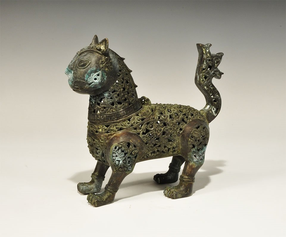 Islamic Style Lion Incense Burner: An undated archaistic openwork bronze censer formed as a standing lion with raised tail, ribbed paws and grotesque face with erect ears and elliptical eyes; the head hinged to the rear of the neck. 86