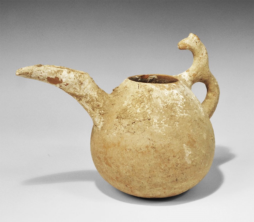 Near Eastern Ceramic Amlash Spouted Vessel: 1st millennium BC. A ceramic vessel of bulbous profile with loop handle formed as the legs of a horse; curved spout with u-section finial. Property of a London gentleman; acquired before 2000. 815 gra