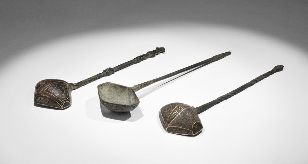 Islamic Bronze Sherbet Spoon Group: 13th-15th century AD. A mixed group of three sherbet spoons each with inlaid silver detail to the underside of the hexagonal bowl, comprising: one round-section handle, with ribbed neck, balustered fi