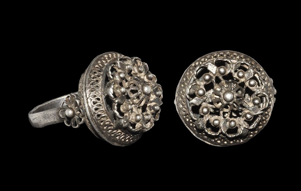 Post Medieval Georgian Silver Pomander Ring: 18th century AD. A barrel-shaped finger ring with openwork filigree bezel, rosettes to the shoulder, granulated rosette to the upper face; stamped maker's mark to the underside of the hoop in the form